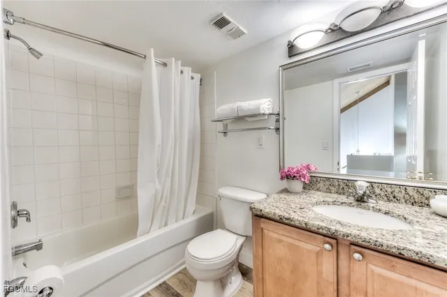 a bathroom with a granite countertop sink toilet mirror and shower