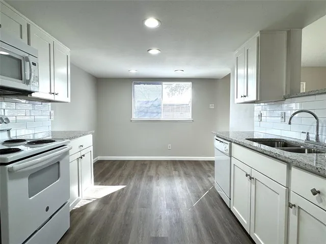 a kitchen with granite countertop wooden floors and white stainless steel appliances
