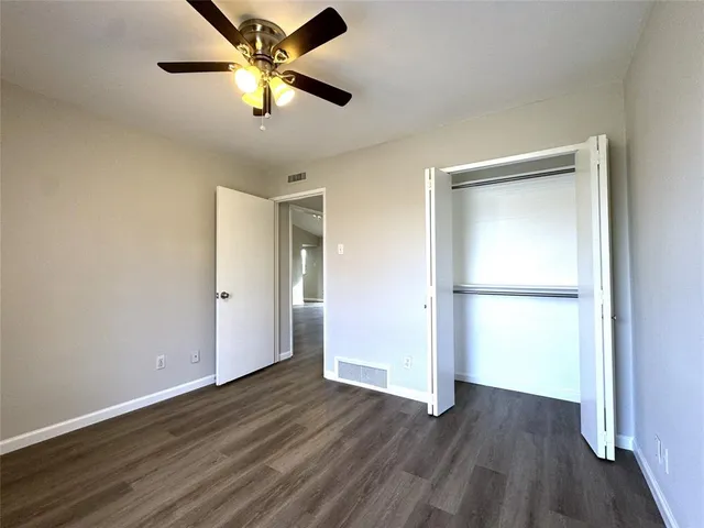 an empty room with wooden floor and a ceiling fan