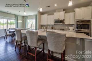 a kitchen with stainless steel appliances granite countertop a stove a sink a microwave a dining table and chairs