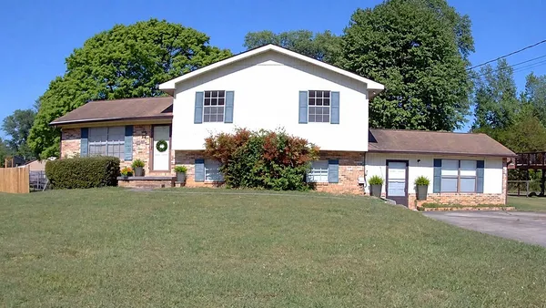 a view of a house with a yard and large tree