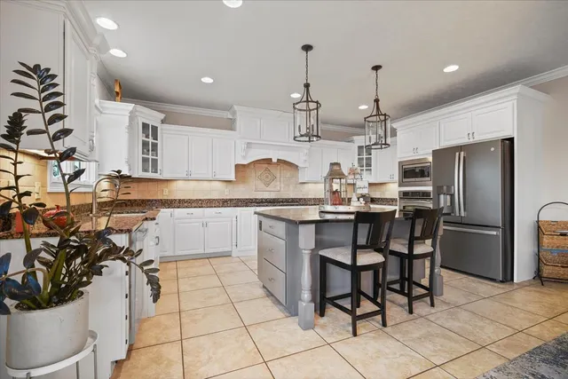 a kitchen with stainless steel appliances kitchen island granite countertop a sink a stove a refrigerator and cabinets