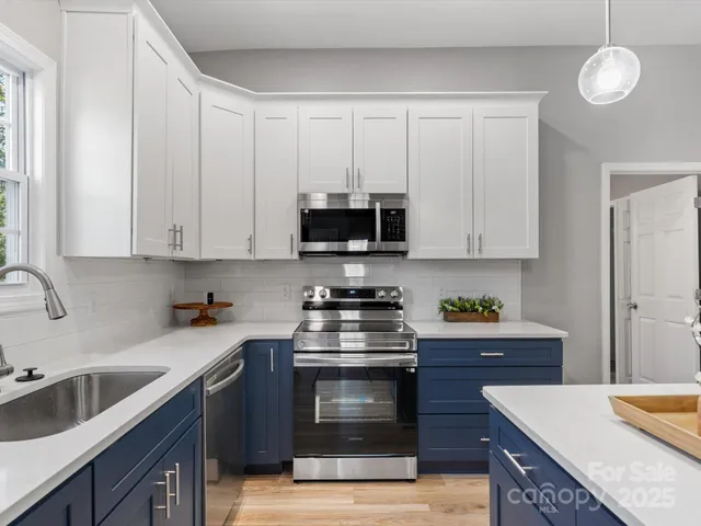 a kitchen with stainless steel appliances granite countertop a stove a sink and a microwave