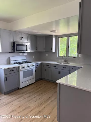 a kitchen with stainless steel appliances granite countertop a sink a stove a refrigerator cabinets and a window