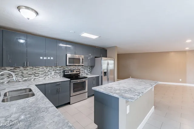 a kitchen with stainless steel appliances granite countertop a sink stove and refrigerator