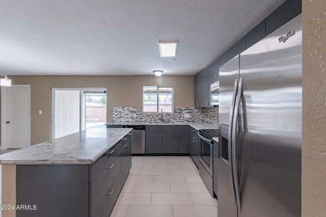 a large kitchen with stainless steel appliances granite countertop a stove top oven a sink and a refrigerator