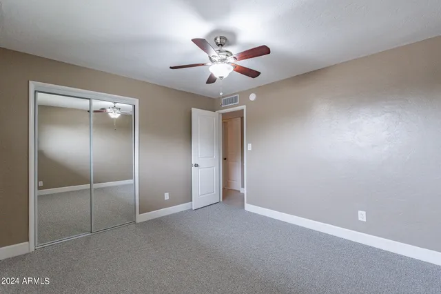 an empty room with windows and fan