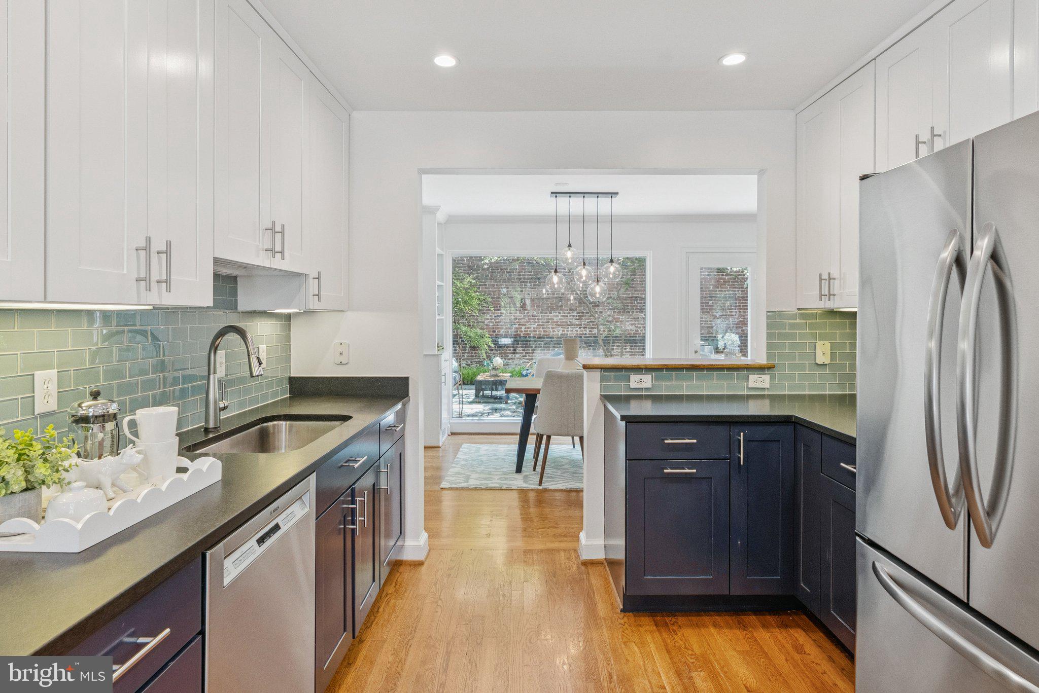 657 E Street Southeast Washington, DC 20003 - Photo 10 of 41 a kitchen with stainless steel appliances granite countertop a refrigerator a sink dishwasher a stove and a dining table with wooden floor