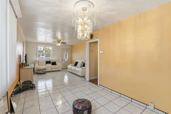 a living room with couches a dining table and a chandelier with wooden floor