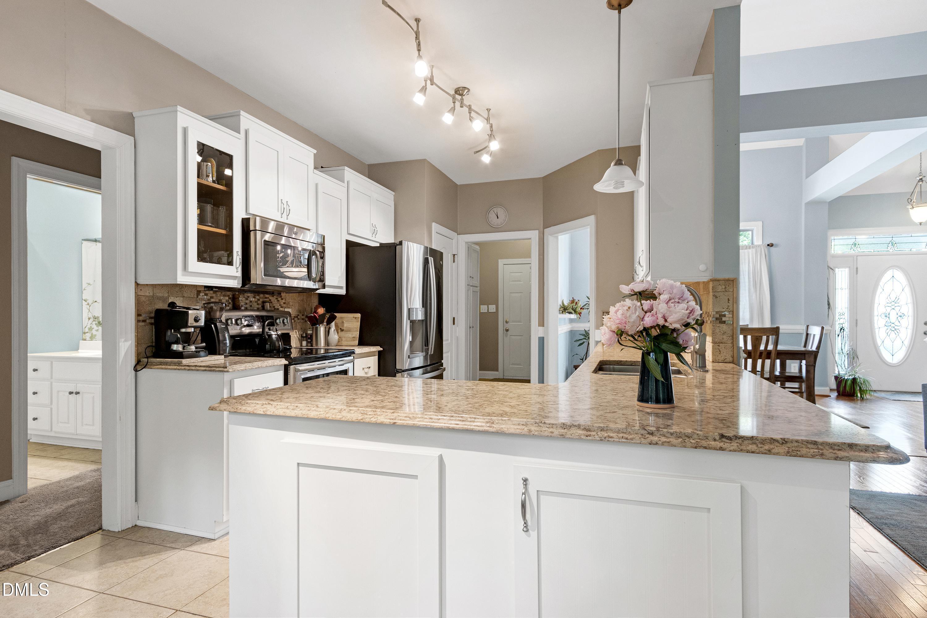 1320 Taylor Farm Road Raleigh, NC 27603 - Photo 17 of 56 a kitchen with stainless steel appliances granite countertop a refrigerator a sink dishwasher and white cabinets with wooden floor