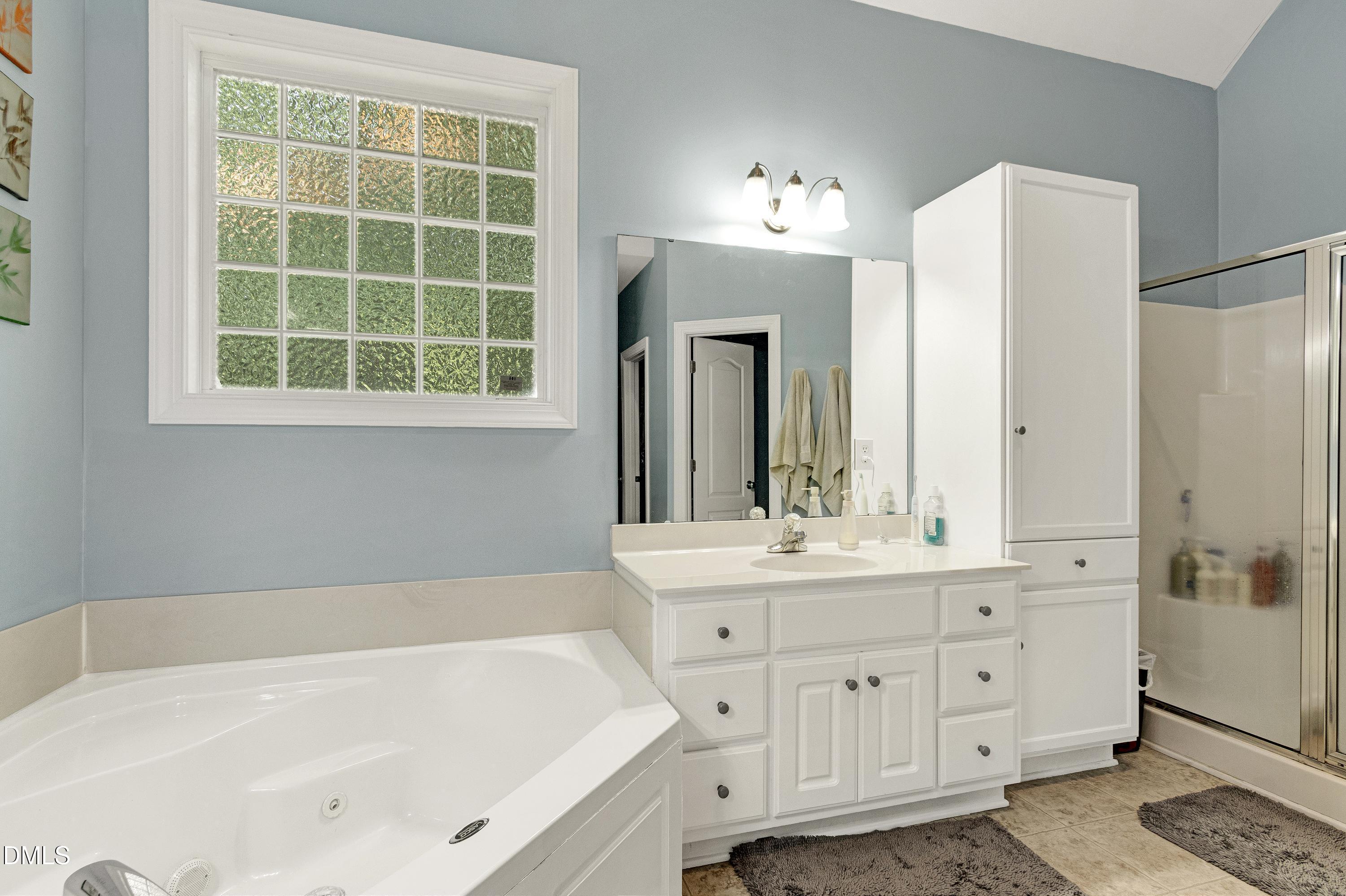 1320 Taylor Farm Road Raleigh, NC 27603 - Photo 26 of 56 a bathroom with a tub a sink and a large mirror