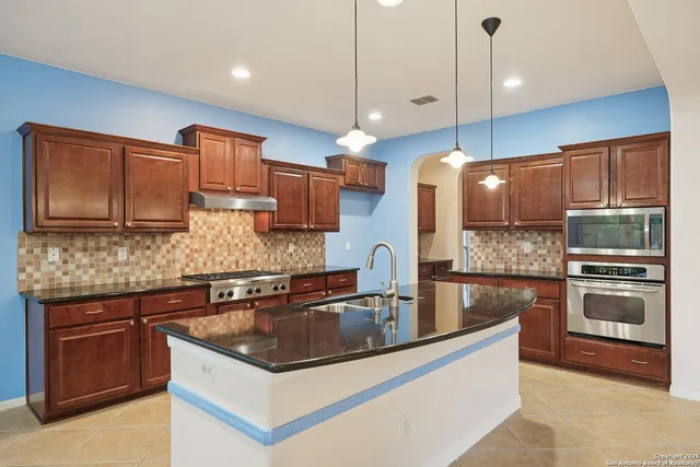 a kitchen with stainless steel appliances granite countertop a sink a stove and a refrigerator
