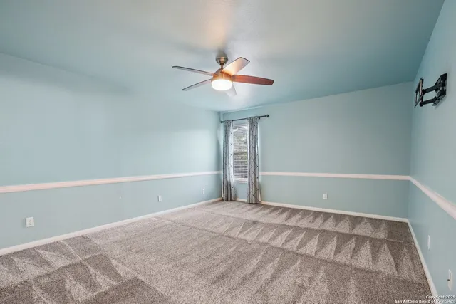 a view of empty room with window and ceiling fan