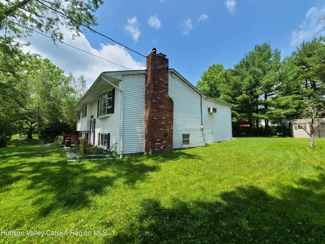 a backyard of a house with plants and large tree
