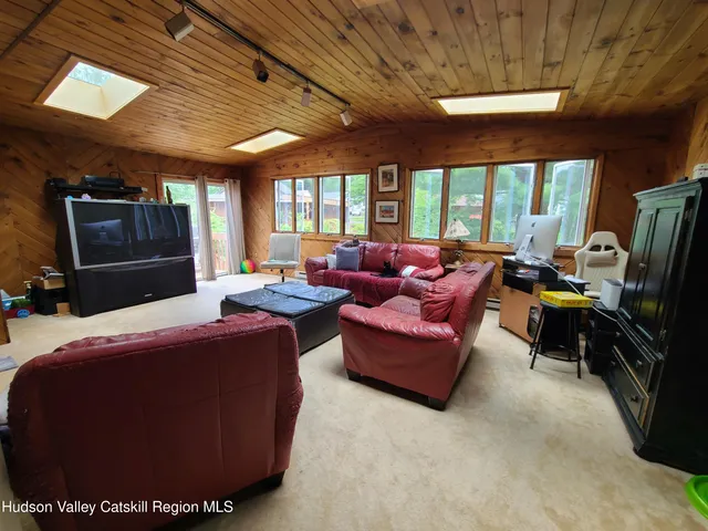 a living room with furniture a flat screen tv and floor to ceiling window