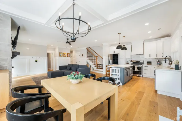 a kitchen with stainless steel appliances kitchen island granite countertop a sink a stove a dining table and chairs with wooden floor