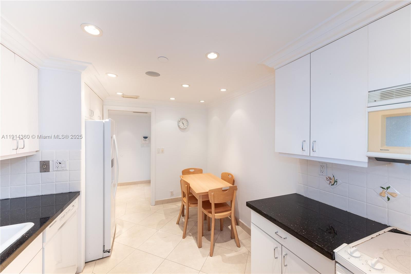 151 Crandon Boulevard, Unit 1036 Key Biscayne, FL 33149 - Photo 10 of 28 a kitchen with a sink and chairs