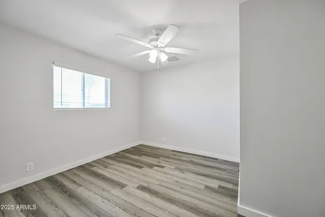 an empty room with a window and a fan