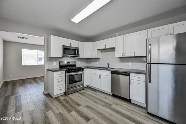 a kitchen with granite countertop white cabinets and stainless steel appliances