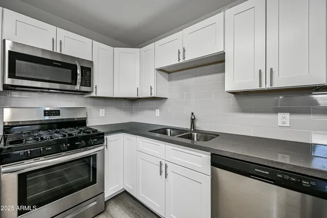 a kitchen with white cabinets and black appliances