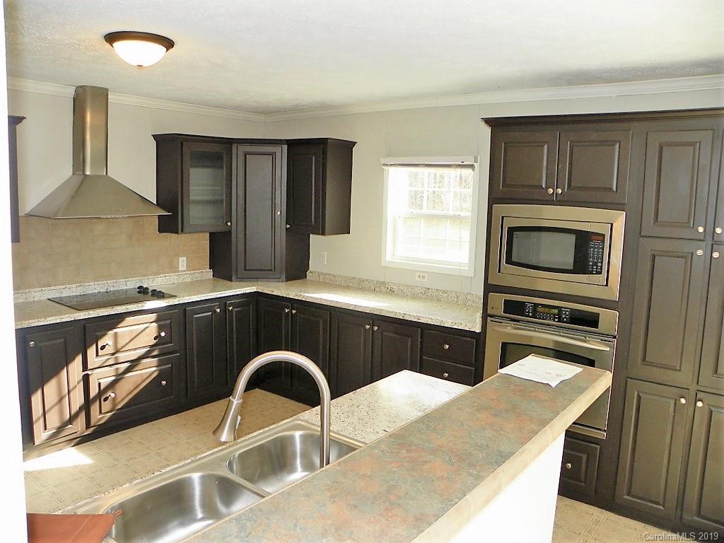 2001 Silver Creek Road Mill Spring, NC 28756 - Photo 14 of 31 a kitchen with granite countertop a stove a sink and a microwave