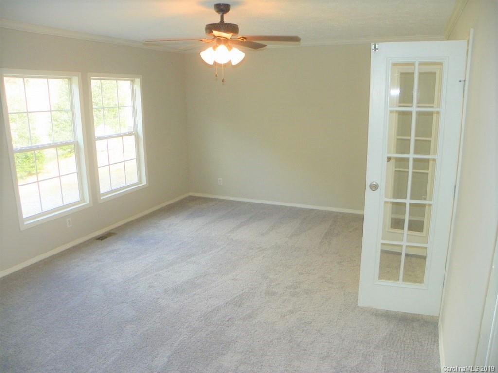 2001 Silver Creek Road Mill Spring, NC 28756 - Photo 19 of 31 an empty room with windows and chandelier fan