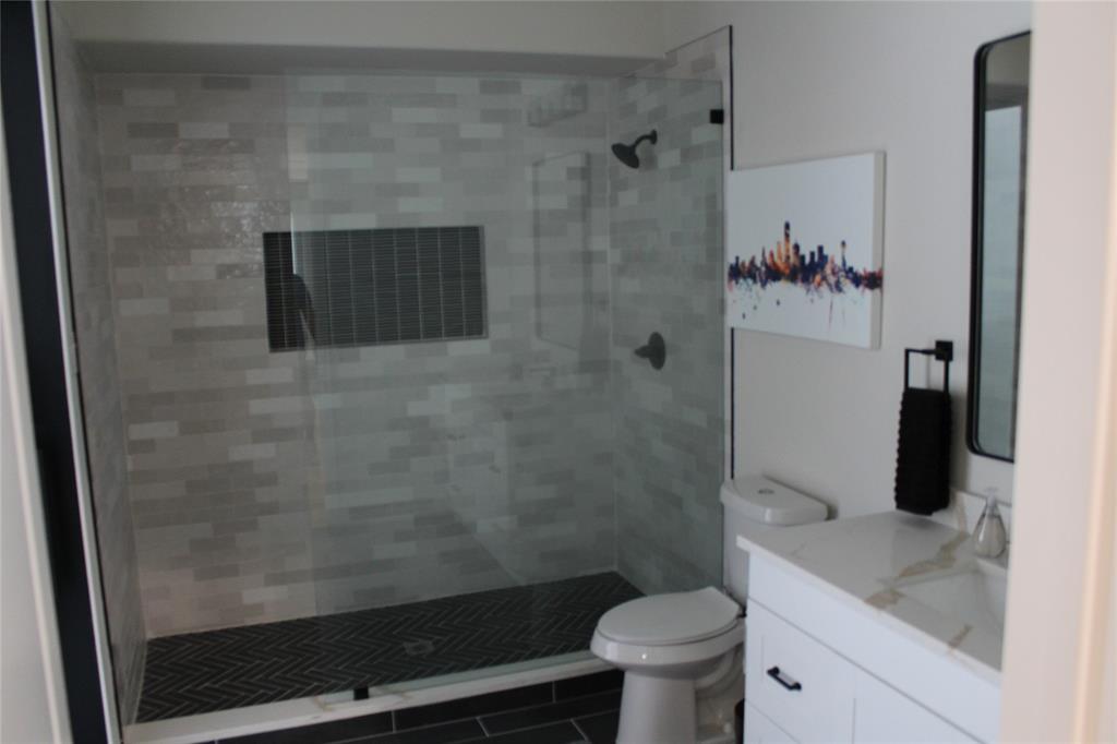 333 Renaissance Lane Heath, TX 75032 - Photo 26 of 35 Modern bathroom featuring a glass-enclosed shower with subway tile walls and a dark herringbone pattern floor