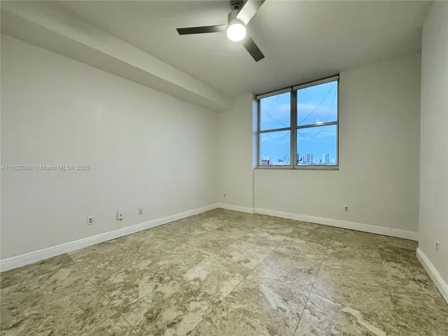 an empty room with a chandelier fan and windows