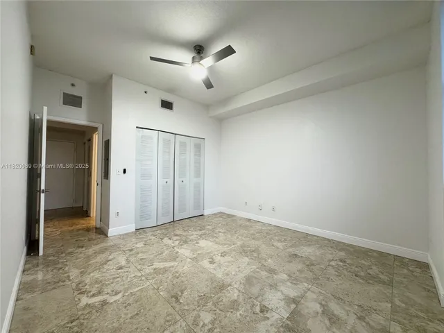 an empty room with closet and a ceiling fan
