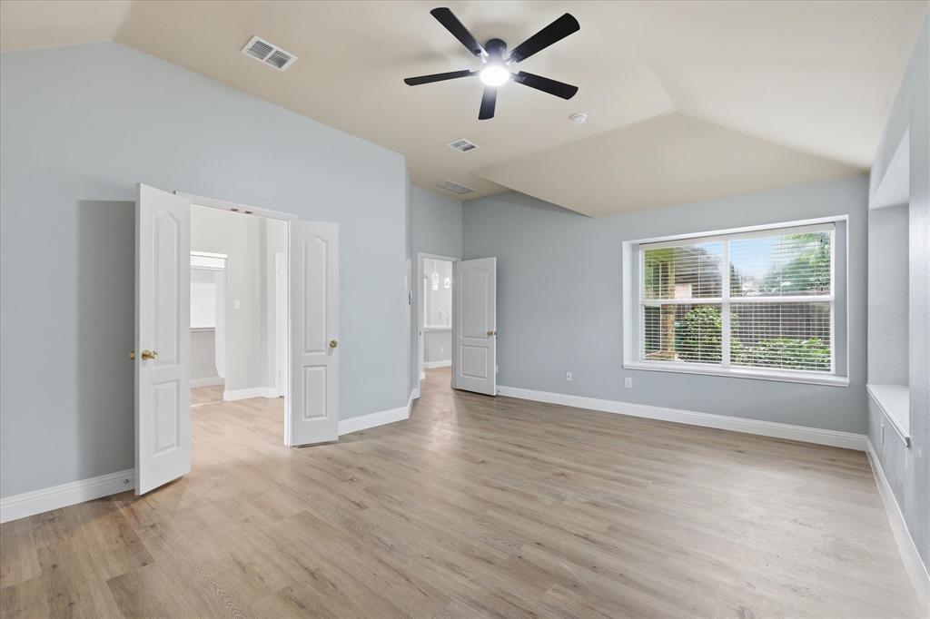 2616 Hollow Ridge Drive Denton, TX 76210 - Photo 17 of 31 Spacious room featuring vaulted ceilings, light wood-finish flooring, a ceiling fan, and large windows with blinds