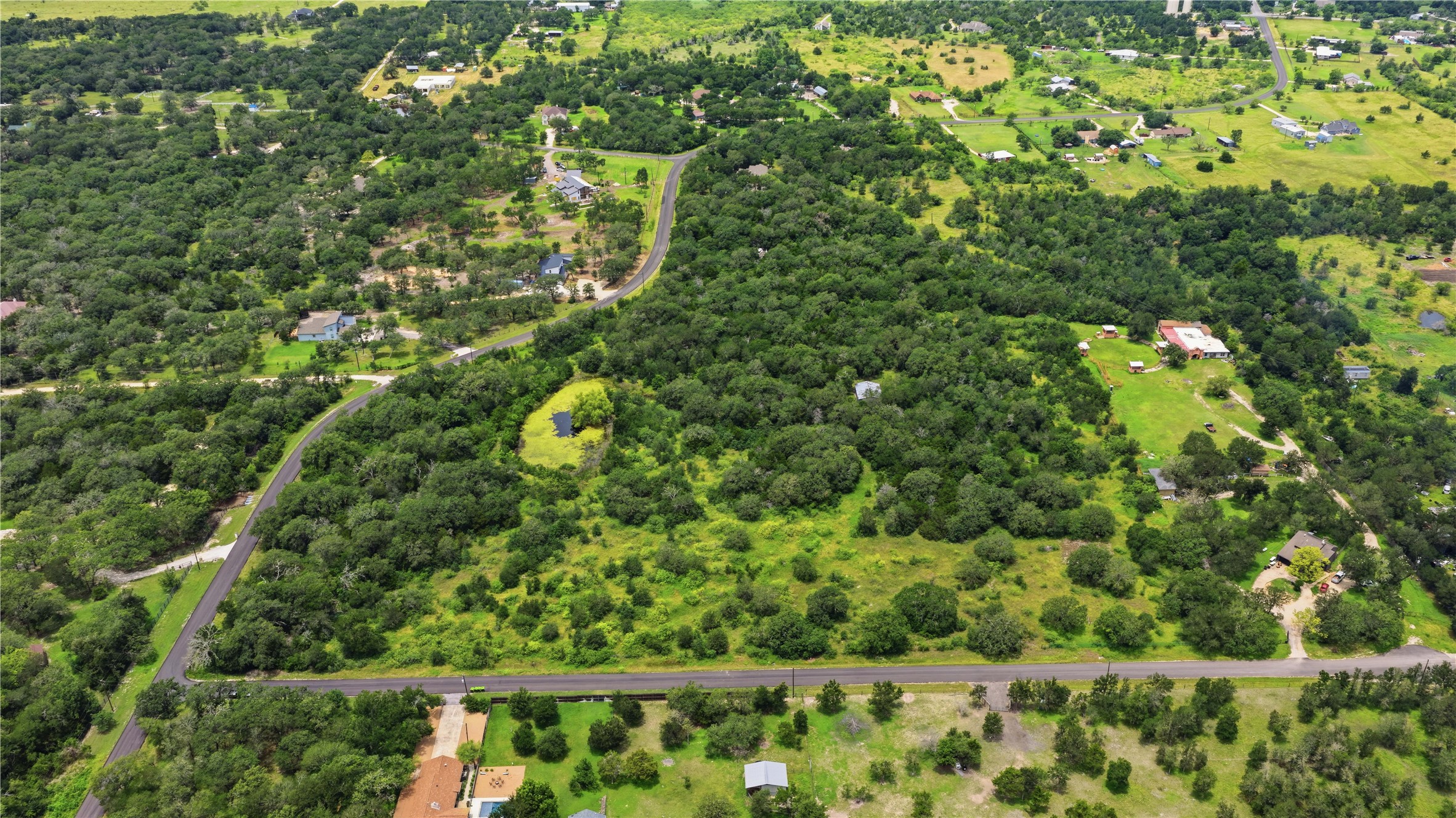 10312 Parsons Road Manor, TX 78653 - Photo 11 of 26 A verdant, sprawling landscape offers a serene escape with mature trees and a tranquil pond.