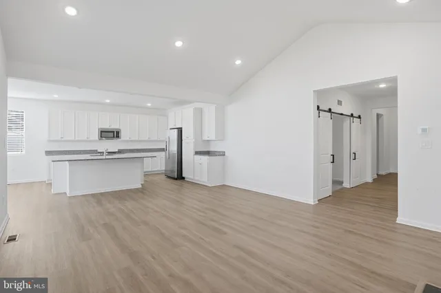 a view of an empty room with wooden floor fireplace and a window