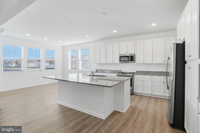 a kitchen with stainless steel appliances granite countertop a sink a stove a refrigerator and cabinets