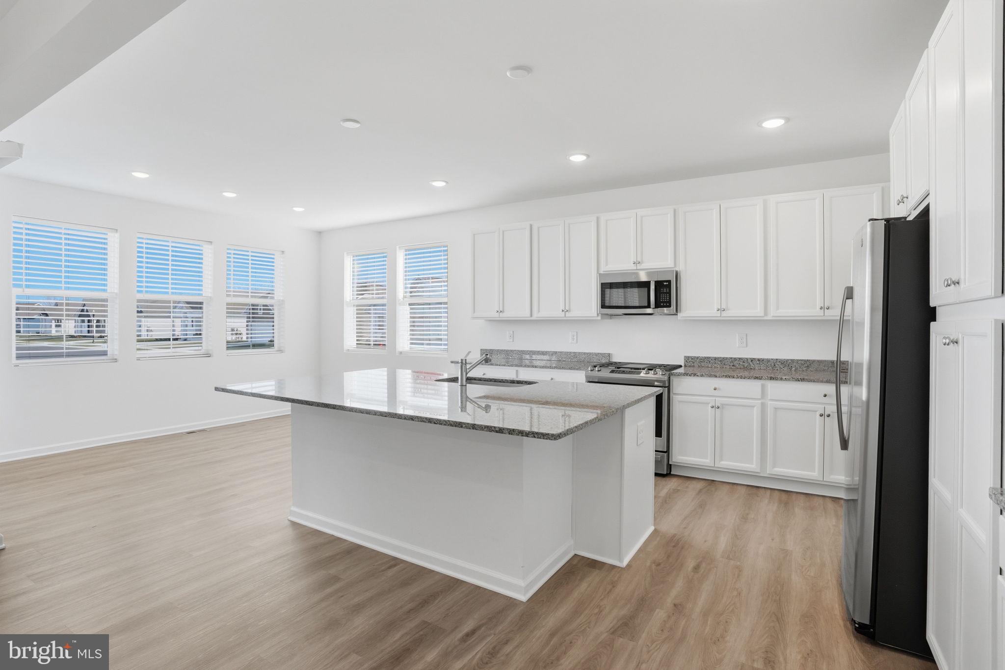 23402 Buttonbush Way Millville, DE 19967 - Photo 30 of 52 a kitchen with stainless steel appliances granite countertop a sink and cabinets with wooden floors