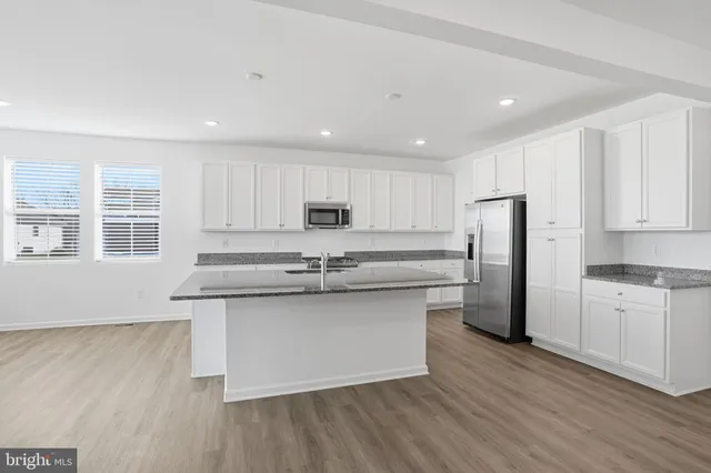 a large kitchen with granite countertop a sink a counter space stainless steel appliances and cabinets