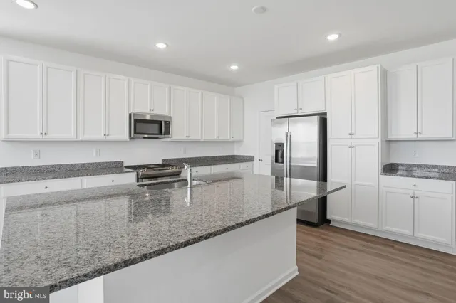 a kitchen with granite countertop white cabinets and stainless steel appliances