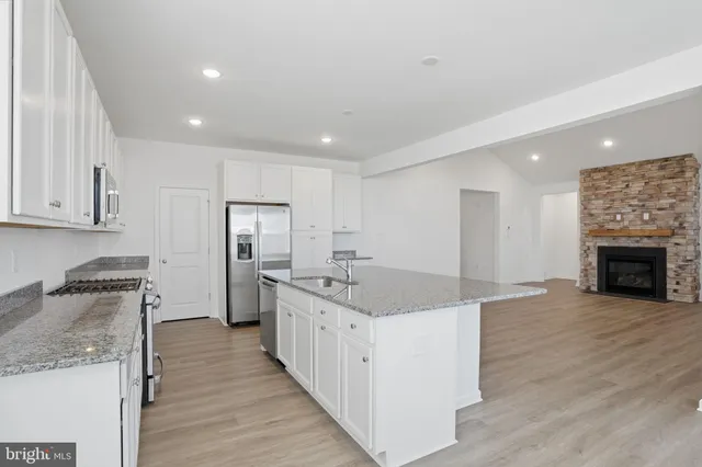 a kitchen with stainless steel appliances granite countertop a stove cabinets and wooden floor