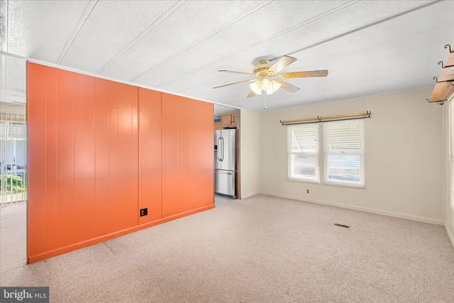 a view of an empty room with chandelier fan and a window
