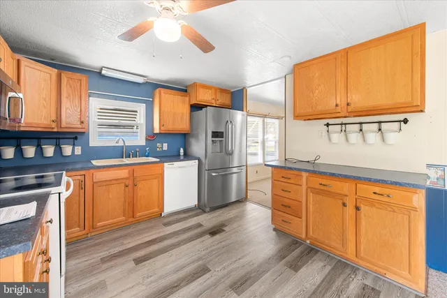 a kitchen with stainless steel appliances granite countertop a stove a sink dishwasher a refrigerator with wooden cabinets and floor