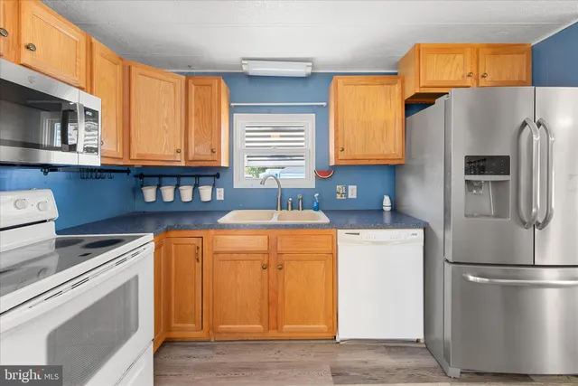 a kitchen with stainless steel appliances granite countertop a refrigerator a stove a sink and a microwave