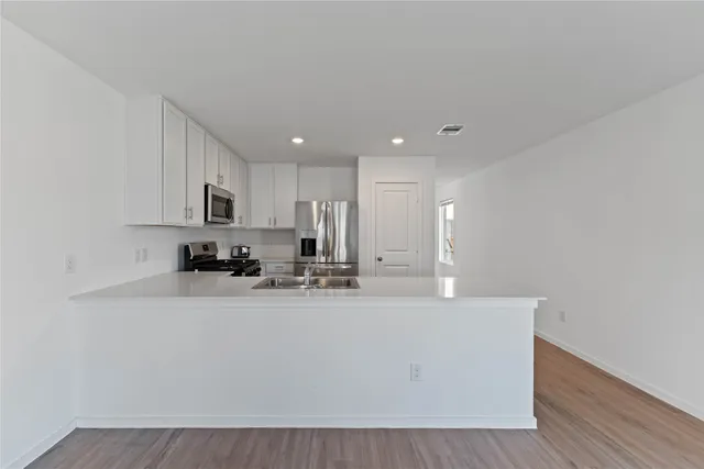 a view of a kitchen with kitchen island a sink wooden floor and counter top space