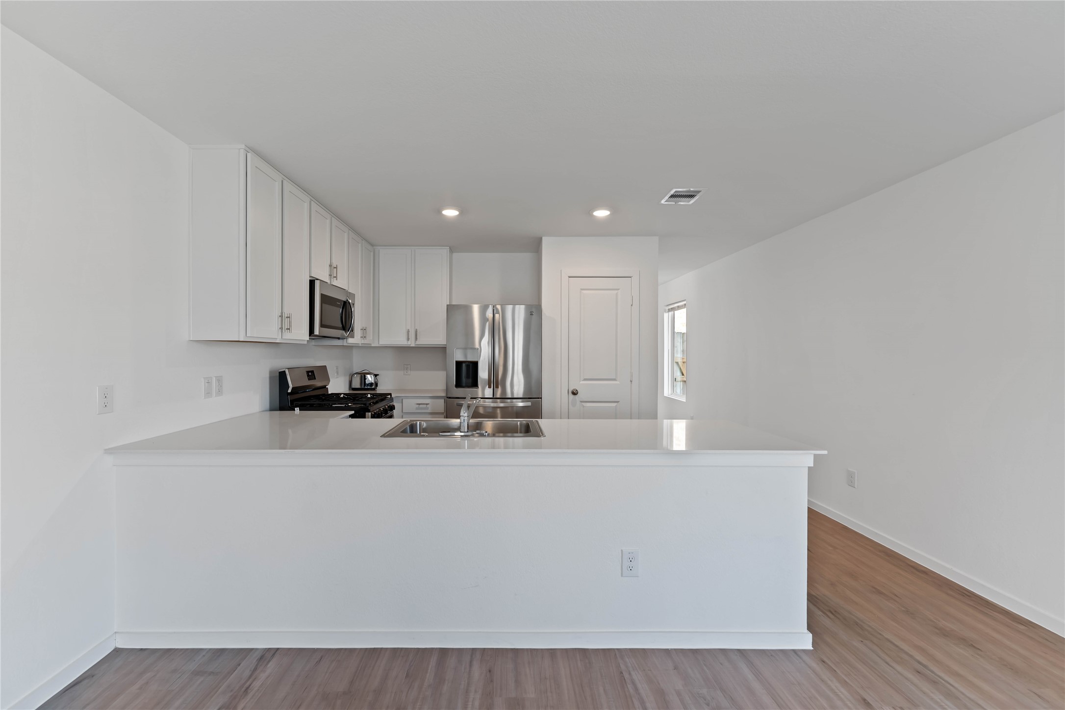 21002 Longwitton Lane Humble, TX 77338 - Photo 7 of 26 a view of a kitchen with kitchen island a sink wooden floor and counter top space