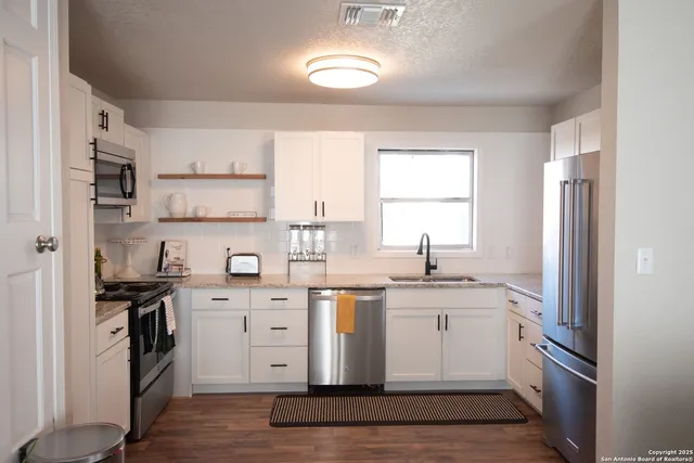 a kitchen with a sink cabinets stainless steel appliances and a window