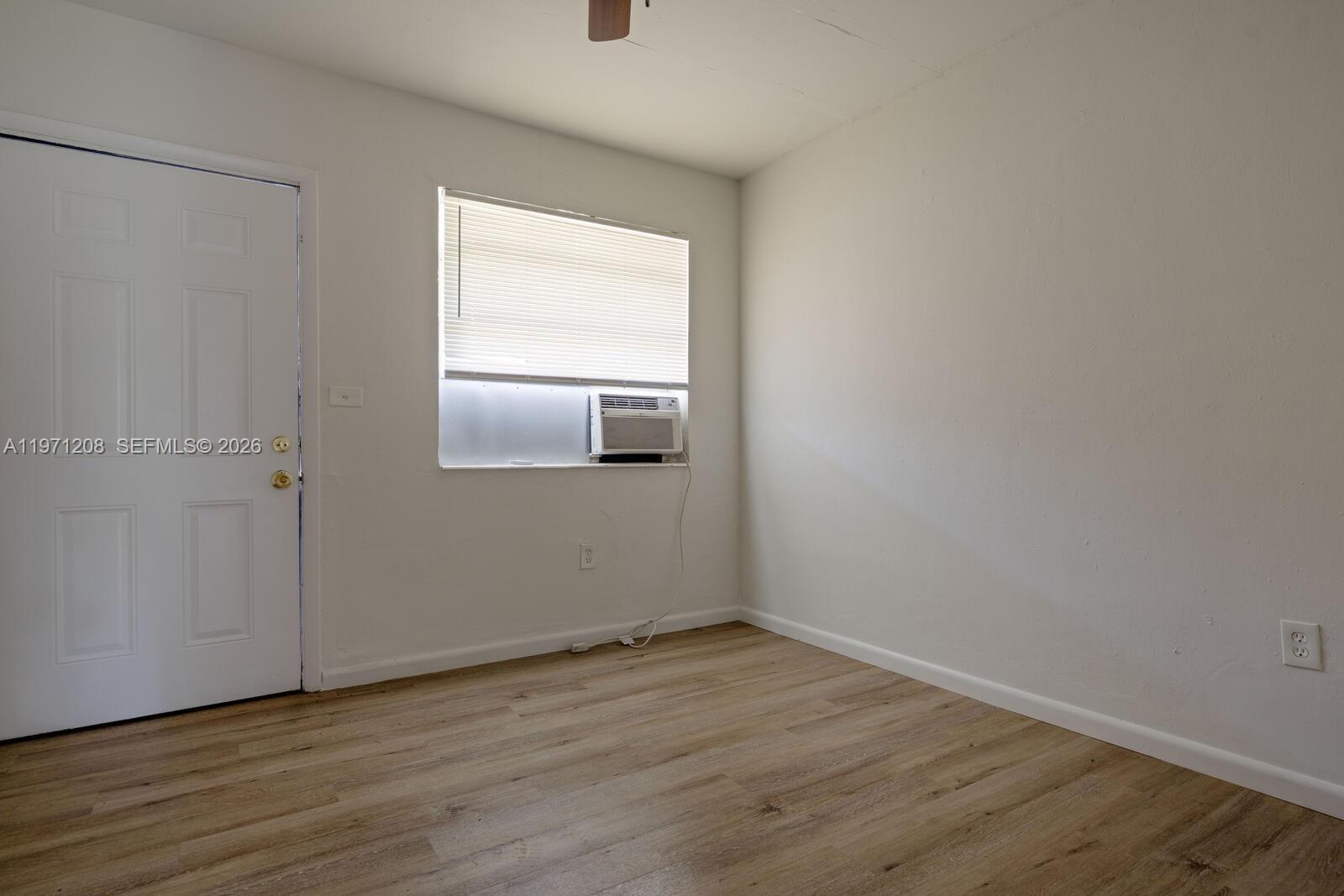 26701 Southwest 137th Avenue, Unit 4 Homestead, FL 33032 - Photo 2 of 7 a view of an empty room with wooden floor and a window
