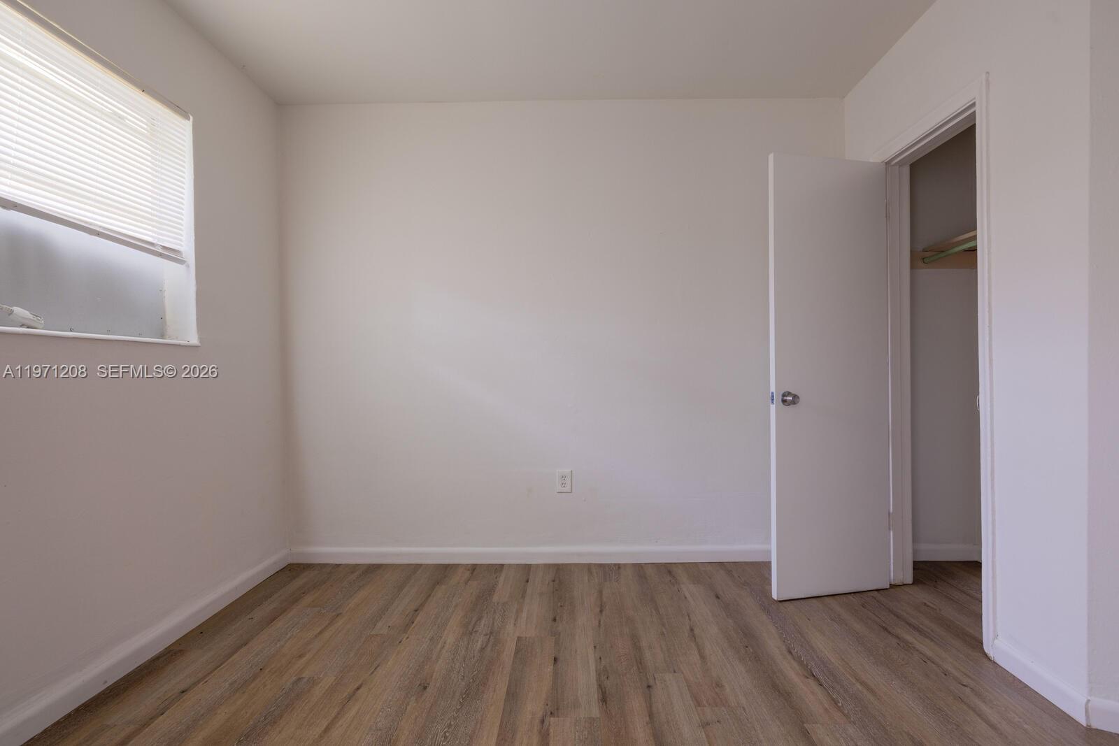 26701 Southwest 137th Avenue, Unit 4 Homestead, FL 33032 - Photo 4 of 7 a view of an empty room with wooden floor and a window