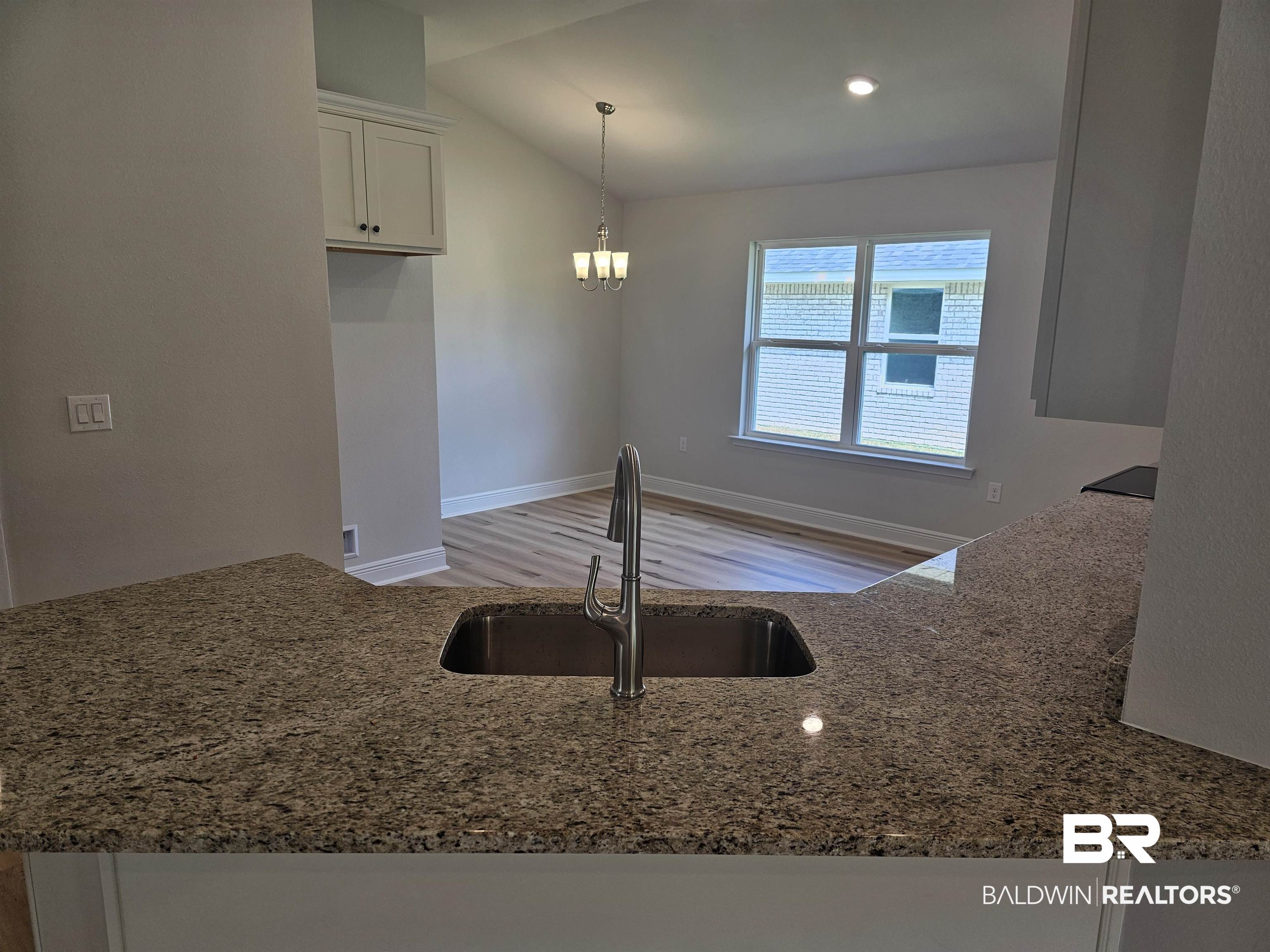 650 Revere Street Foley, AL 36535 - Photo 31 of 34 Kitchen featuring light hardwood / wood-style floors, vaulted ceiling, white cabinets, stone countertops, and sink