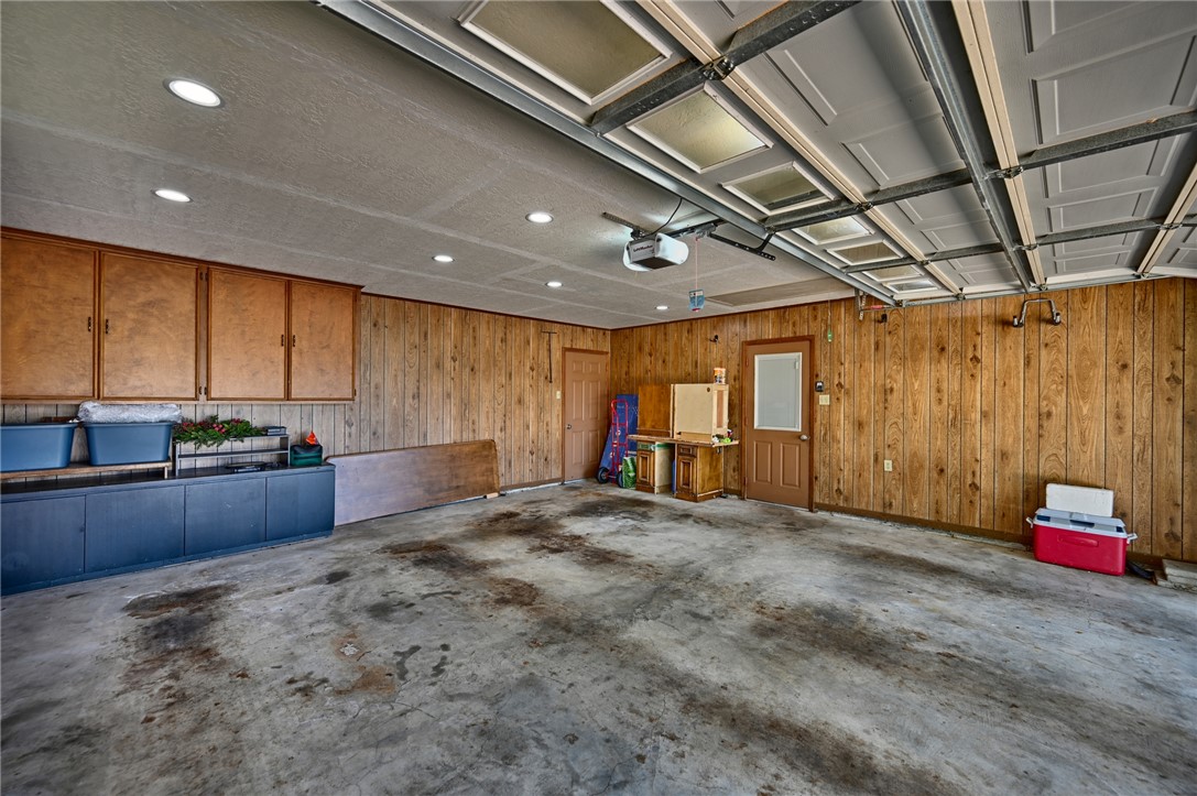1600 Pecan Street Brenham, TX 77833 - Photo 27 of 33 Garage featuring a garage door opener, wooden walls, built in cabinets and recessed LED lighting