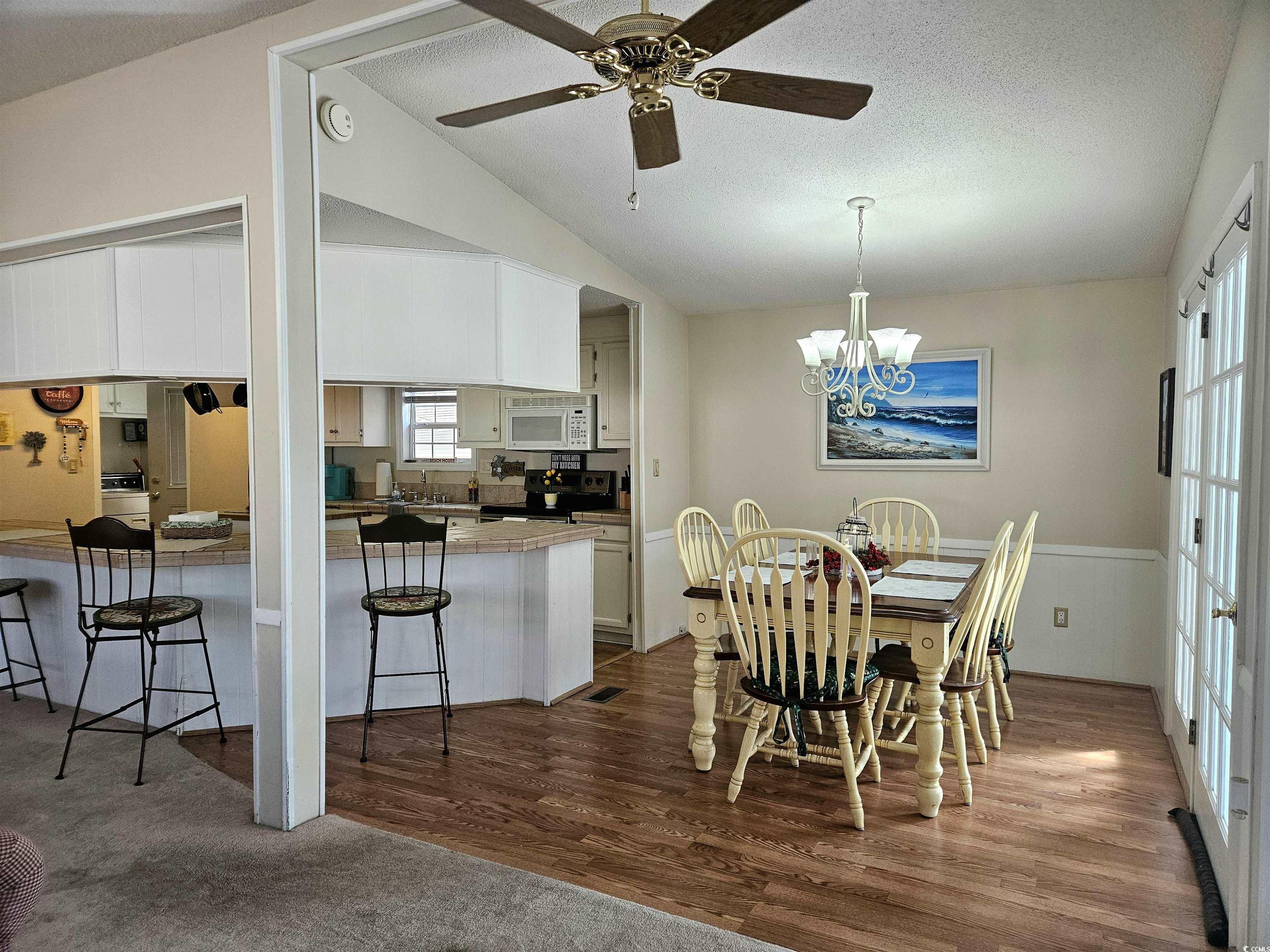 471 Meadowlark Surfside Beach, SC 29575 - Photo 6 of 40 Dining area featuring a chandelier, dark wood-type flooring, a textured ceiling, ceiling fan, and vaulted ceiling