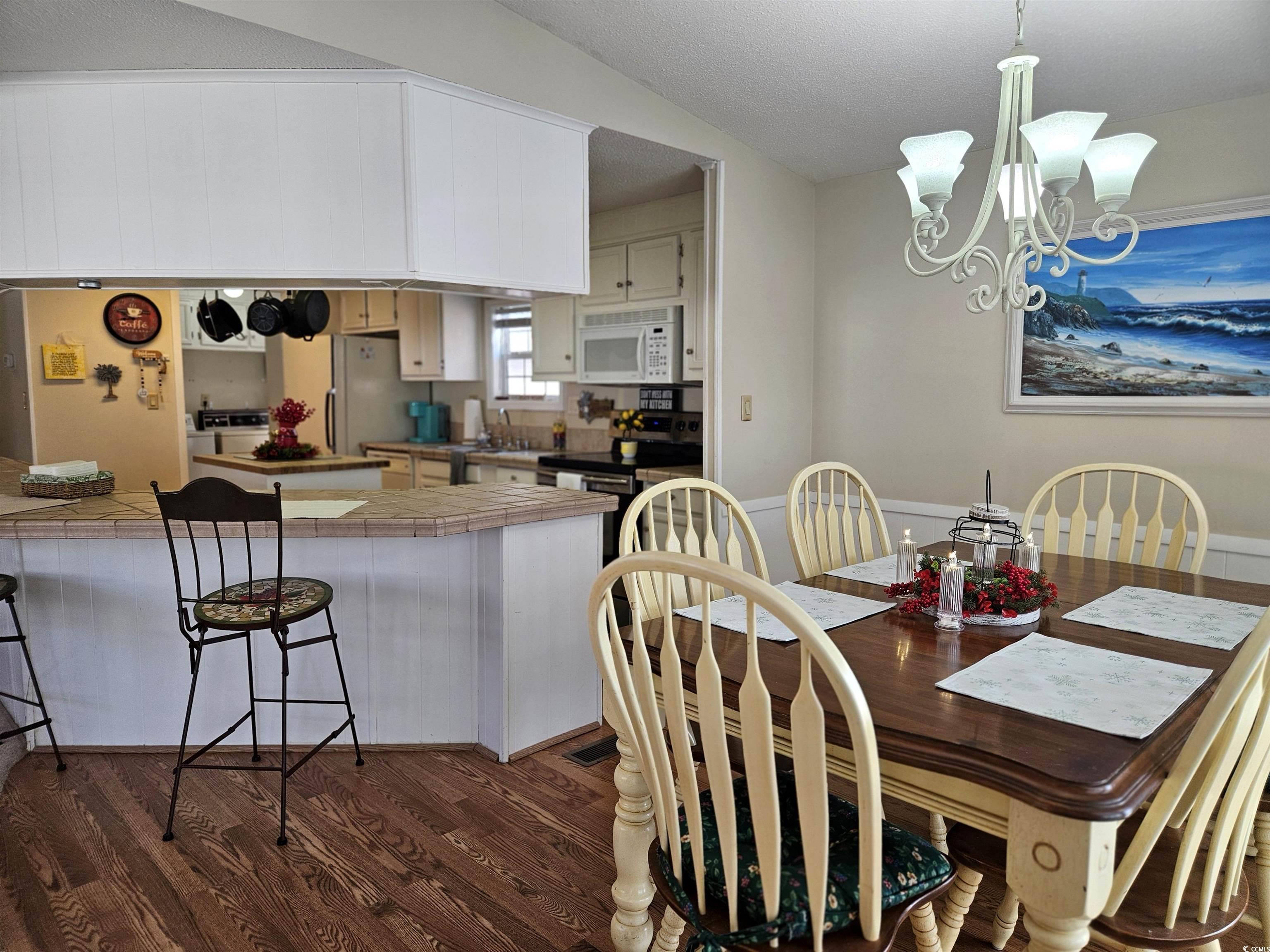 471 Meadowlark Surfside Beach, SC 29575 - Photo 7 of 40 Dining area with dark wood-style floors, a textured ceiling, a chandelier, and lofted ceiling