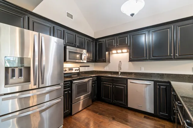 a kitchen with stainless steel appliances granite countertop a refrigerator a stove and a sink